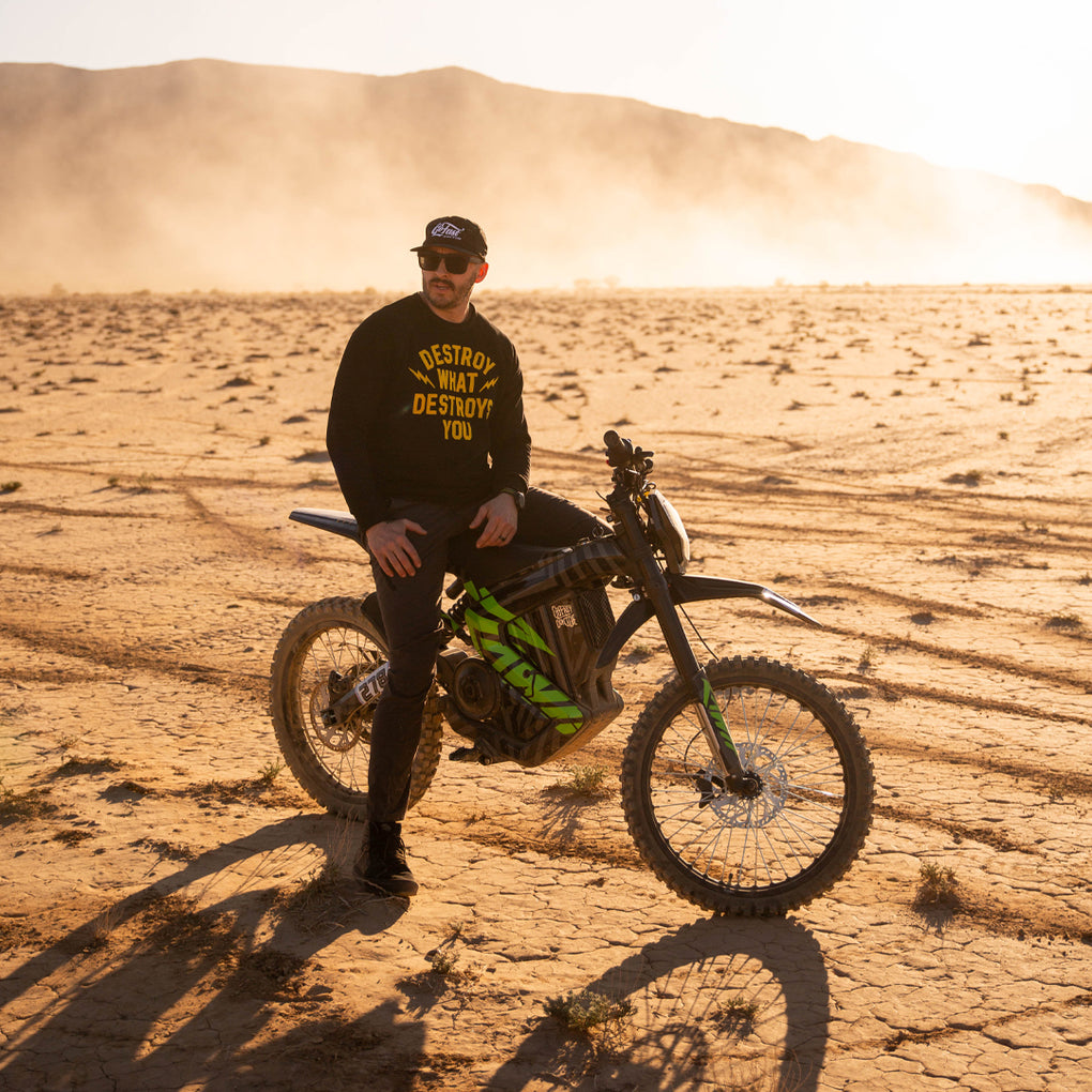 A man sitting on RAWRR mantis model on desert ground